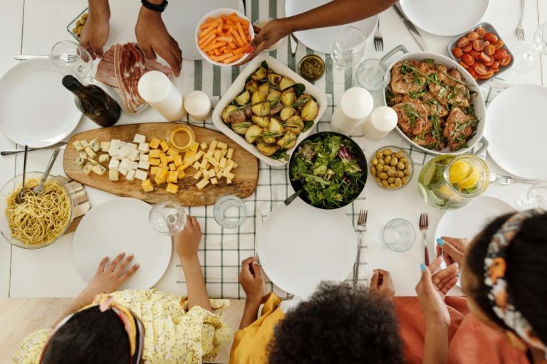 A family sharing a meal with food platters on the table, allowing children to choose their own portions to support intuitive eating and body trust.
